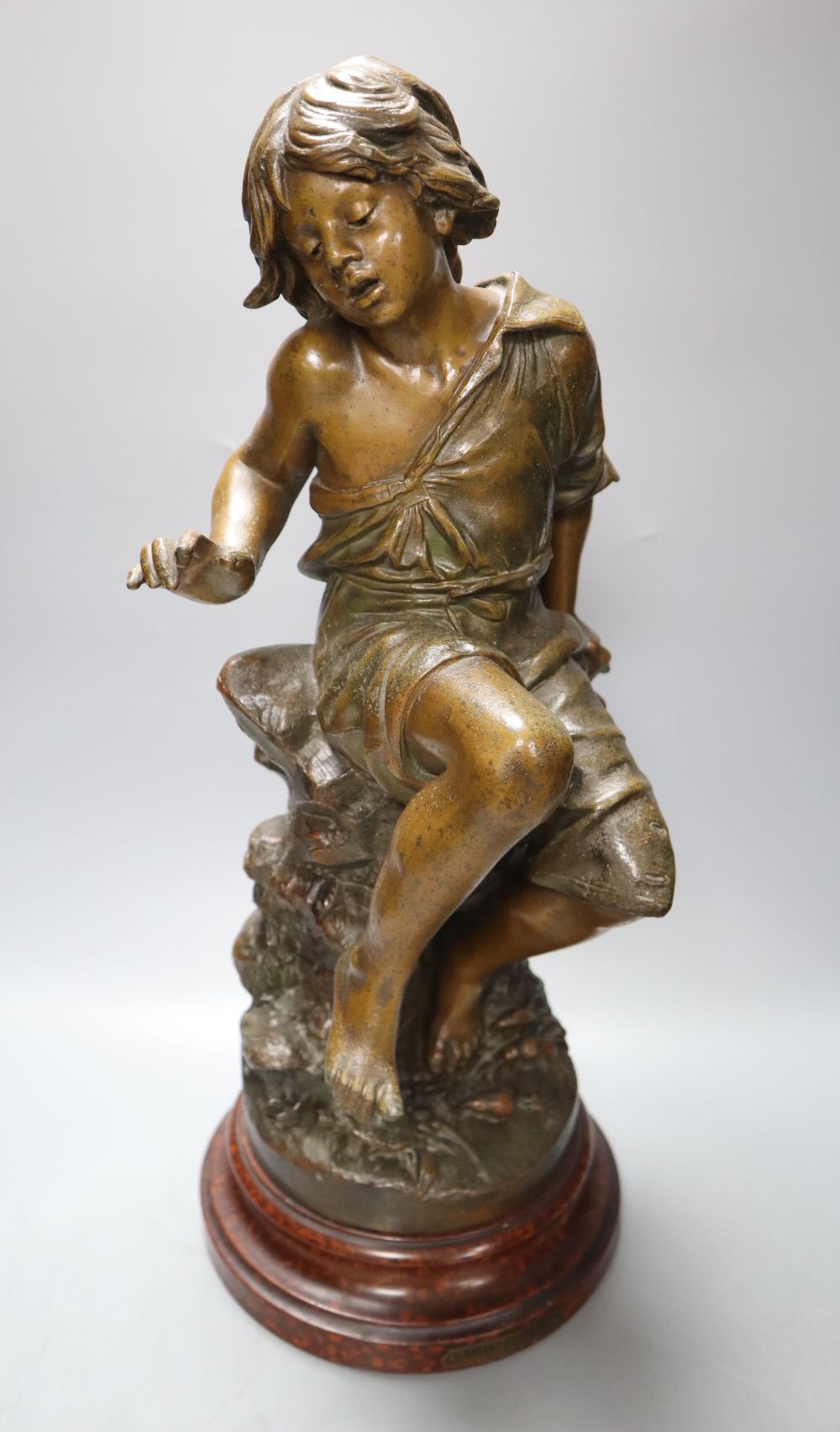 After August Moreau. A patinated spelter model of a seated youth, Enfant au Crabe, on marbled wood plinth, 49cm